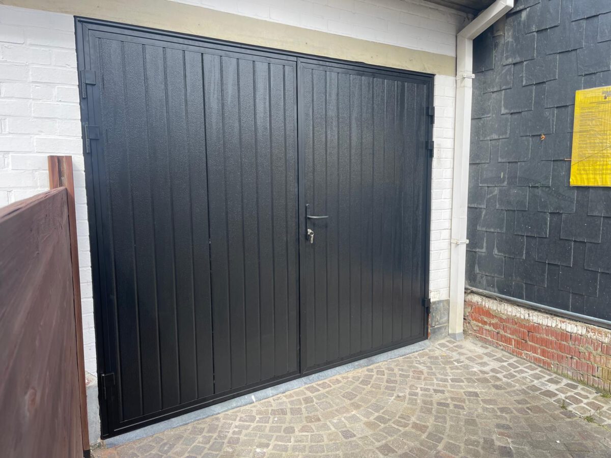 Op maat gemaakte openslaande garagedeur met zorgvuldig geplaatste compriband voor optimale afdichting tegen water, lucht en licht.